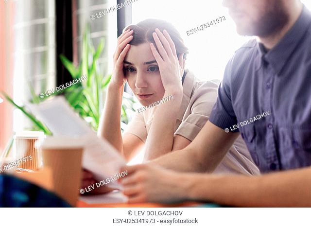 business, startup and people concept - creative team of man and woman with computer and files solving problem in office