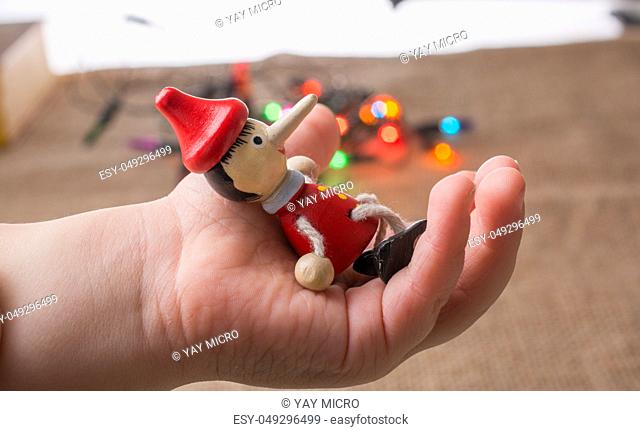 Wooden Pinocchio doll sitting in hand before lights