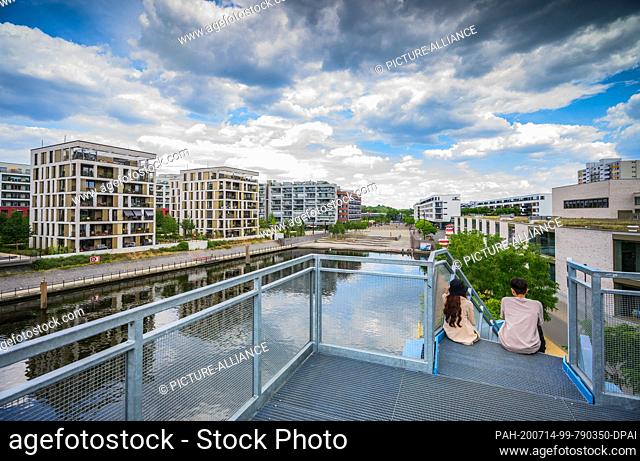 14 July 2020, Hessen, Offenbach: Two young people are sitting on the stairs to the viewing platform. In the former industrial harbour