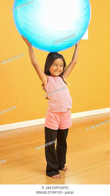 Hispanic girl lifting exercise ball
