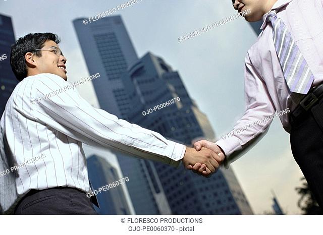 Two businessmen outdoors shaking hands