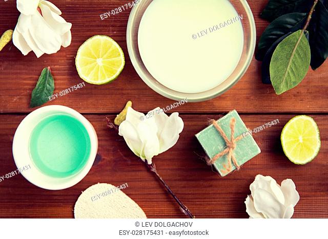 beauty, spa, body care and natural cosmetics concept - close up of bowls with citrus body lotion, cream and soap on wooden table