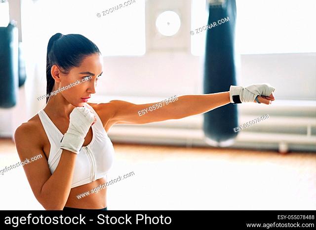 Female boxer practicing her punches at a boxing studio. Athletic woman making direct hit. Sport concept