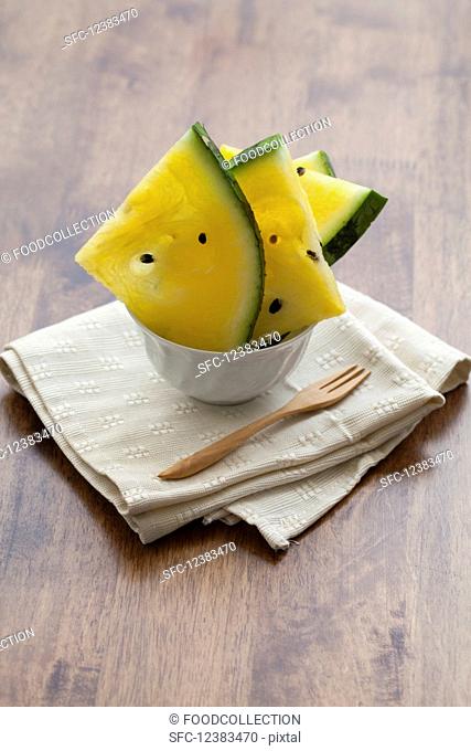 Pieces of yellow watermelon in a bowl on a napkin