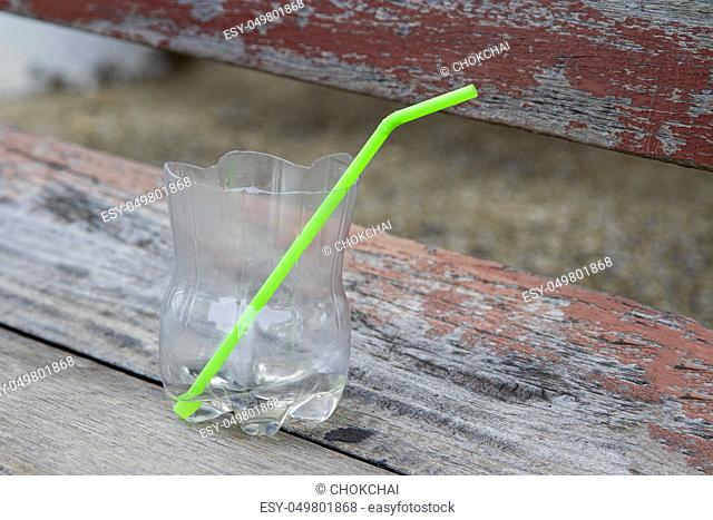 Clear plastic glass with green tube on the wooden desk