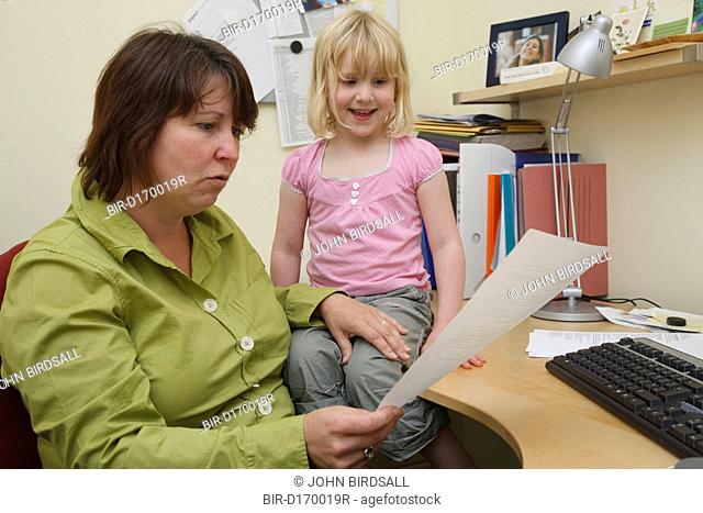 Mother in office trying to work being disturbed by daughter
