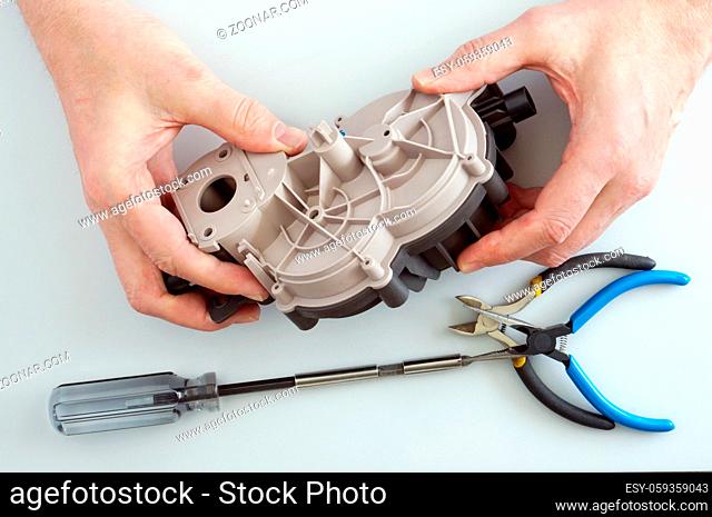 Old elderly home craftsman repairs the gearbox from electric meat mincer. Home closeup shot