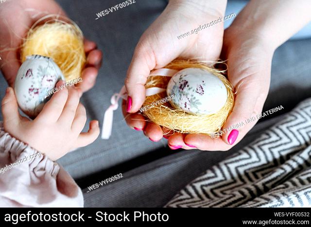 Easter eggs held by mother and daughter at home