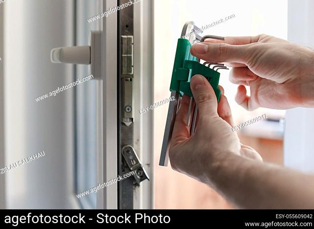 Man's hand choose allen key for adjustment of hardware of the uPVC door mechanism