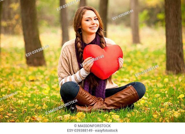 Girl with toy heart at autumn park