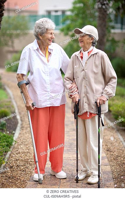 Two senior women strolling in retirement villa garden