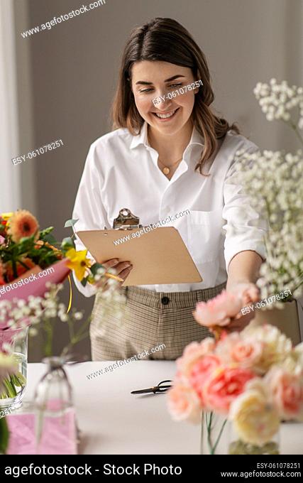 happy woman with clipboard and flowers at studio