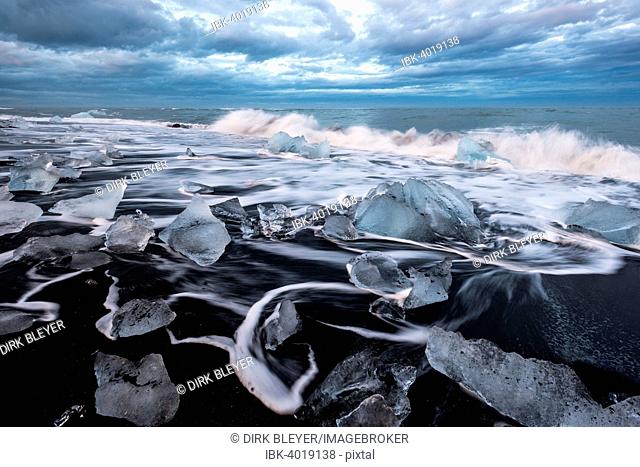 Pieces of ice on black beach lapped by the sea, at the Jökulsárlón glacier lagoon, Vatnajokull Glacier, Eastern Region, Iceland