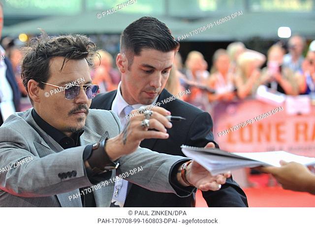 FILE - A file picture dated 19 July 2013 shows US actor Johnny Depp signing autographs during the premiere of his film Lone Ranger, in Berlin, Germany