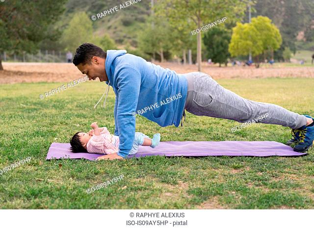 Father exercising with baby in park