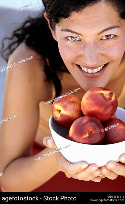 Young woman holding bowl of nectarines