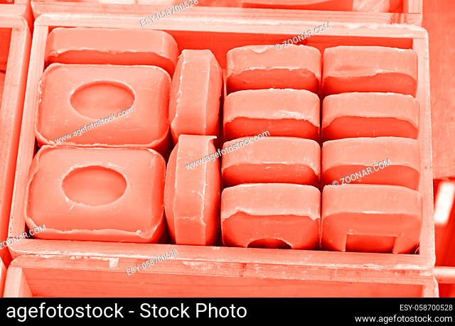 Close up coral pink toned traditional beauty toilet hard soap bars in wooden box on retail display, high angle view