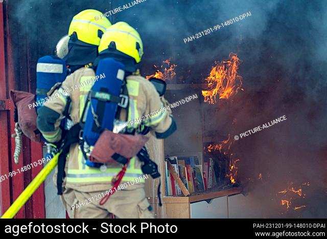 01 December 2023, Berlin: Firefighters extinguish a simulated room fire during a demonstration of a fire during the Christmas season on the grounds of the...