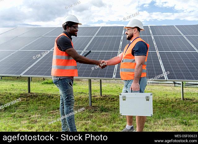 Engineer shaking hand with colleague at solar station