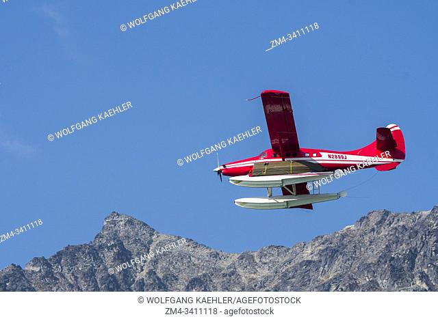 A red seaplane is flying over Lake Crescent in Lake Clark National Park and Preserve, Alaska, USA