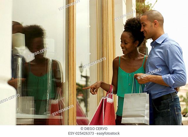 Portrait of black tourist heterosexual couple in Panama City with shopping bags. The man and his girlfriend look at shop window