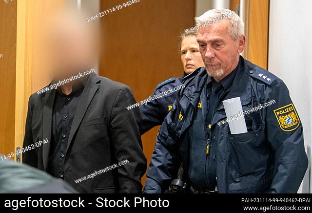14 November 2023, Bavaria, Augsburg: Two police officers lead a defendant into a courtroom at the regional court. Two men are once again on trial in Augsburg...