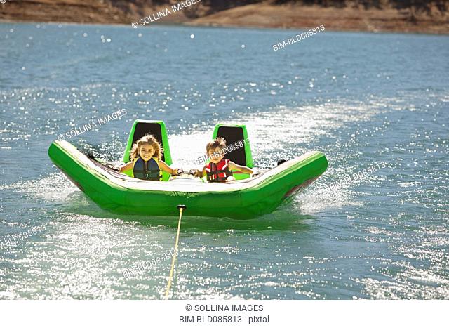Children riding inflatable raft on lake