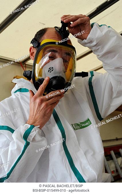 Preparing a worker on an asbestos removal site in the north of France. Regulatory clothing for each worker consists of overalls, a mask, boots and gloves