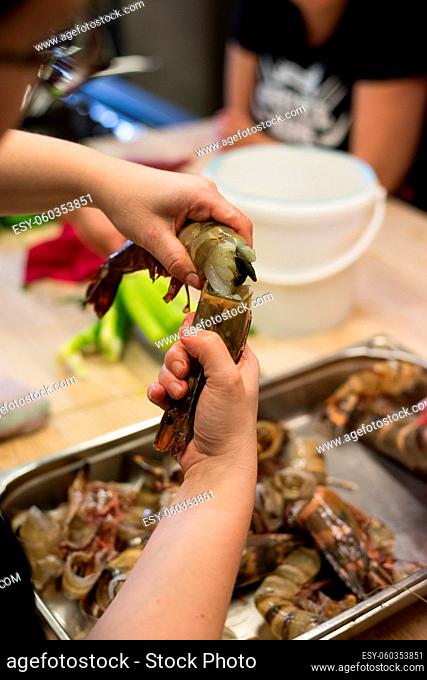 Human hands breaking up shell of Norway lobster in kitchen during cookery class
