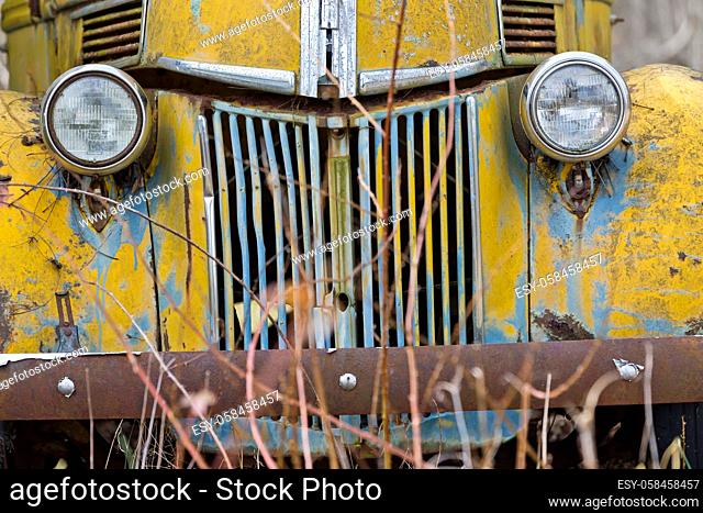 An old abandoned car sits in a field as it rusts away