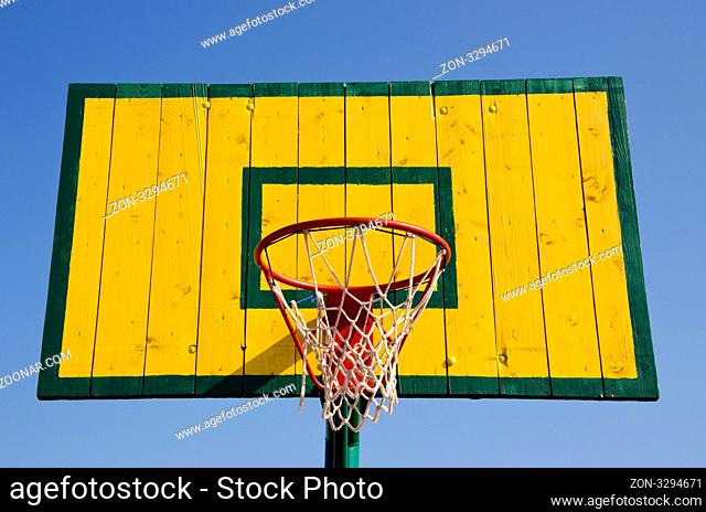 Basketball board painted green and yellow with net on the hoop