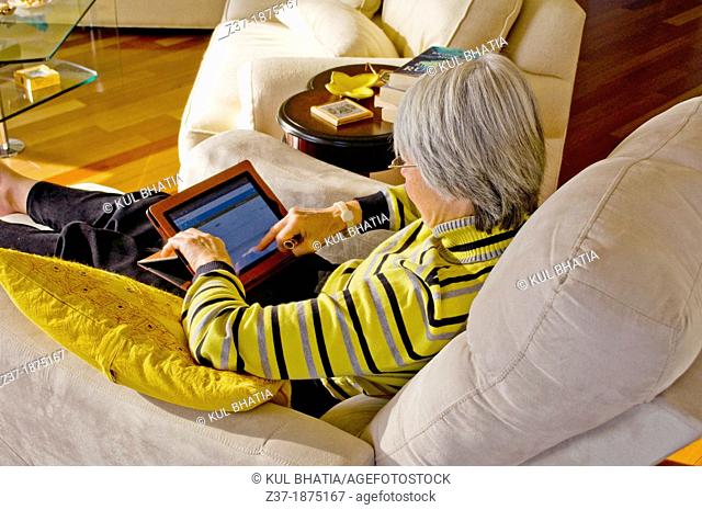 A woman with a tablet relaxes in her well-appointed living room, Etobicoke, Canada