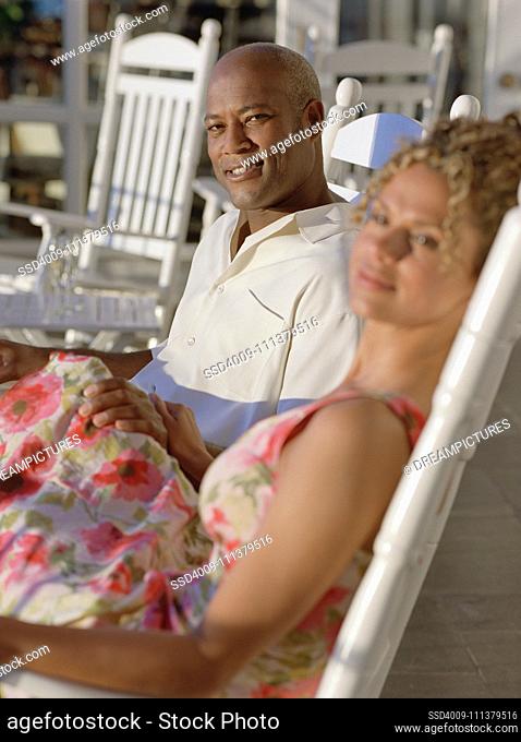 Middle-aged African American couple sitting in rocking chairs outdoors