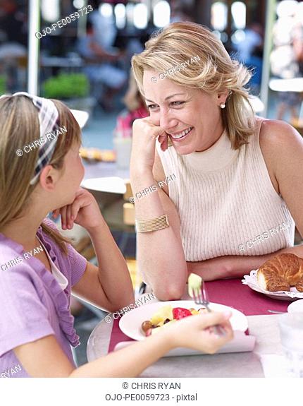 Woman and young girl on outdoor patio eating meal