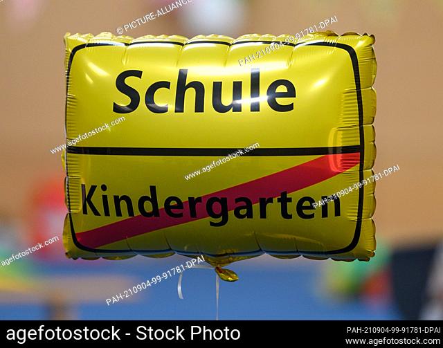 04 September 2021, Saxony, Dresden: A balloon in the shape of an entrance sign to a town with the words ""Schule"" (school) and a crossed-out ""Kindergarten""...
