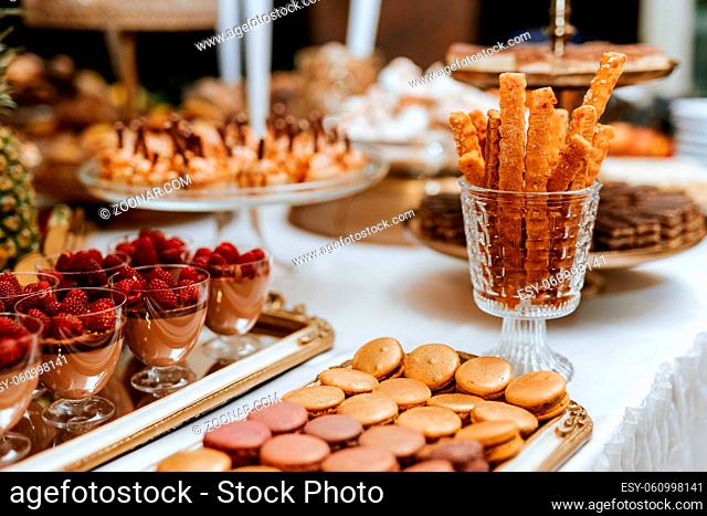 Wedding candybar with desserts, creamy and colorful pastries, delicious cookies, ananas, macarons, muffins