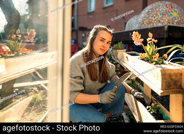 Portrait of young woman working in garden in sunshine