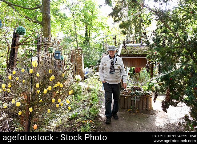02 October 2021, Saxony, Leipzig: Fritz Hundt walks past a shrub adorned with packaging for toys in ""his"" Hundt Park. Since 1981