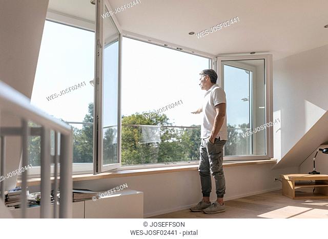 Mature man standing at the window in empty room