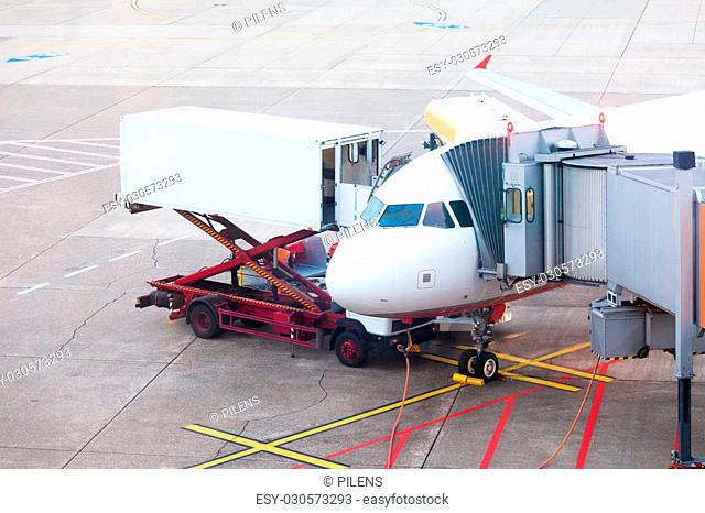 Airliner being prepared for boarding and takeoff on airport docked to terminal and serviced