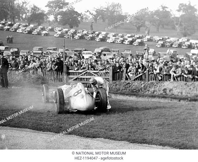 Dick Seaman with his Mercedes, Donington Grand Prix, 1938. Seaman has got out of the car and is examining one of the rear wheels after spinning off on lap 27...