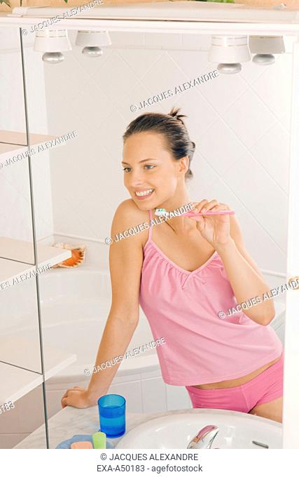 Young girl in the bathroom brushing her teeth in the morning