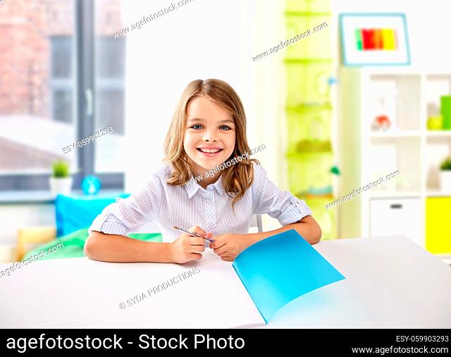 happy student girl with notebook and pen at home