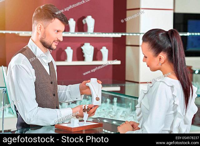 Treating herself. Cheerful dark haired female customer examining a necklace professional jeweler is showing her consumerism people shopping buyer shopper money...