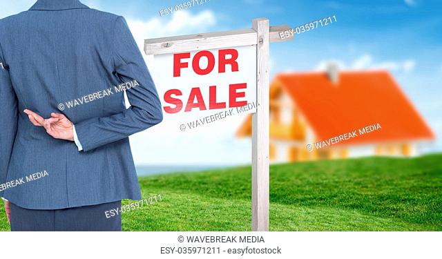 Businesswoman with fingers crossed and For Sale sign