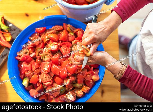 Woman cutting large amount of tomatoes for prepare tomato sauce. Preparation of tomatoes for cooking