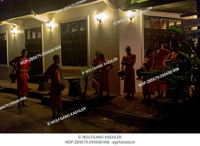 Buddhist monks gathering to receive alms in the early morning before sunrise from the people of the UNESCO world heritage town of Luang Prabang in Central Laos