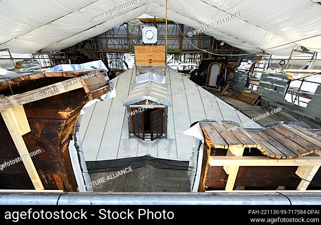 PRODUCTION - 17 November 2022, Berlin: The roof of the palace on Peacock Island, newly covered with zinc sheeting, is under a protective roof and the facade is...
