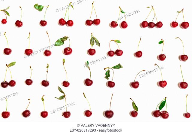 many ripe red cherries with green leaves arranged on white background