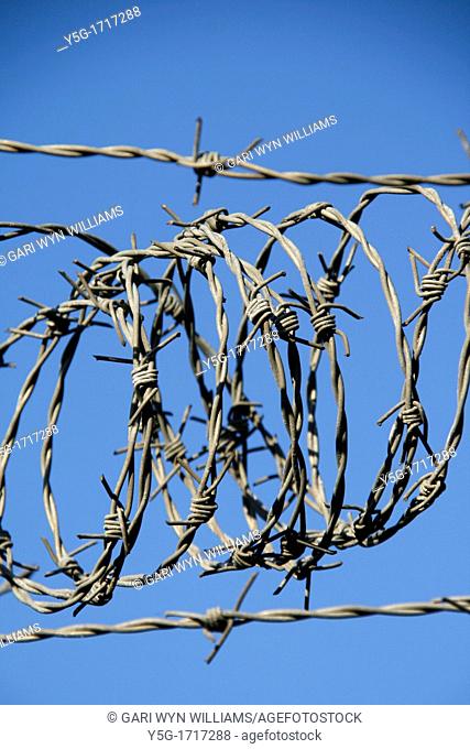 tangled spiral barbed wire fence against blue sky in sun